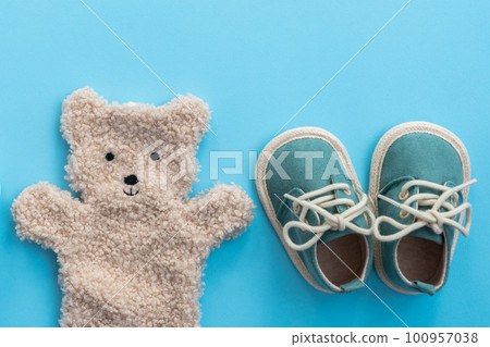 Baby shoes and bear toy on blue paper background. Newborn concept. Top view, flat lay 100957038