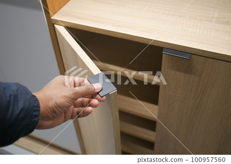 man's hand open drawer wooden in cabinet 100957560