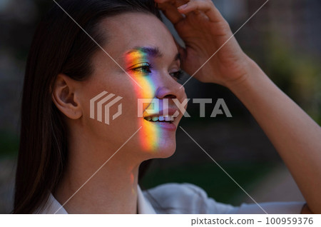 Portrait of caucasian woman with rainbow beam on her face outdoors. Portrait of caucasian woman with rainbow beam on her face outdoors. 100959376