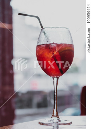 Vertical image wine glass of alcohol cold drink cocktail beverage with black plastic straw. Drops condensation. Close up Vertical image wine glass of alcohol cold drink cocktail beverage with black plastic straw. Drops condensation. Close up 100959424