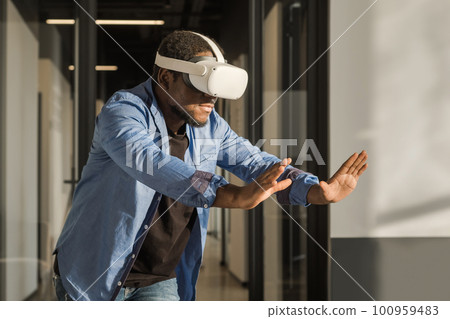 Man in vr headset exploring metaverse world, touching virtual reality subjects. Abstract cyber world in office 100959483