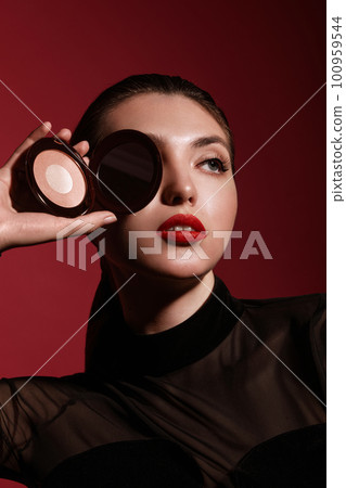 Beautiful woman in black clothes, classic make-up and red lips posing with powder in the studio. Beautiful woman in black clothes, classic make-up and red lips posing with powder in the studio. 100959544