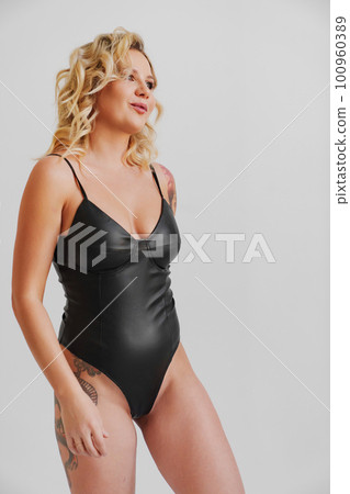 growth portrait. a sexy blonde with tattoos in a leather swimsuit growth portrait. a sexy blonde with tattoos in a leather swimsuit 100960389