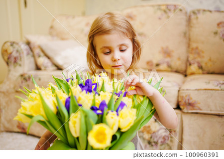 Portrait of a cute little girl with a bouquet of yellow tulips and purple irises Portrait of a cute little girl with a bouquet of yellow tulips and purple irises 100960391