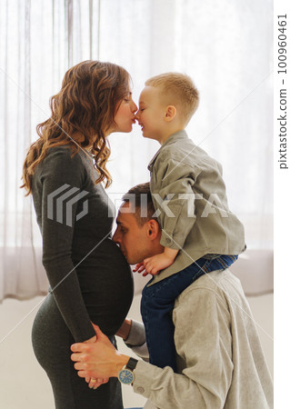 a loving and gentle family. pregnant mom, son sits on dad's shoulders. 100960461