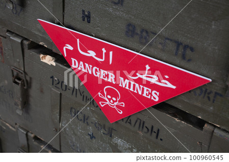 Arabic/English minefield warning red sign - Danger Mines. White skull-and-crossbones on a red. Arabic/English minefield warning red sign - Danger Mines. White skull-and-crossbones on a red. 100960545