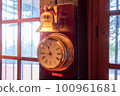 A golden clock shining in the sunlight by the window 100961681