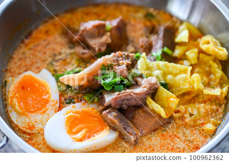 curry bone soup - bone soup pork with boiled eggs in hot pot, Thai food tom yum hot and sour soup 100962362