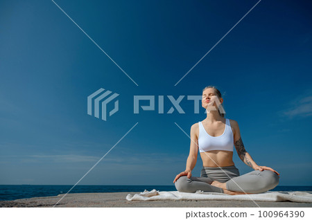 Yoga practice and meditation in nature. Woman practicing near Black sea. 100964390