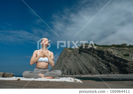 Yoga practice and meditation in nature. Woman practicing near Black sea. Yoga practice and meditation in nature. Woman practicing near Black sea. 100964411