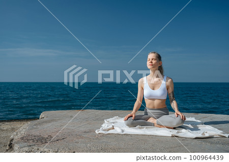 Yoga practice and meditation in nature. Woman practicing near Black sea. 100964439
