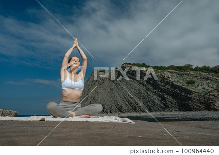Yoga practice and meditation in nature. Woman practicing near Black sea. 100964440