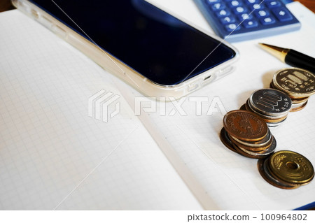 Blank notebook, smartphone, calculator, pen, various coins Blank notebook, smartphone, calculator, pen, various coins 100964802