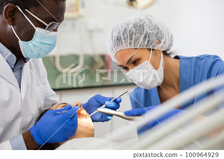 Dentist and nurse performing tooth enamel restoration operation on woman Dentist and nurse performing tooth enamel restoration operation on woman 100964929