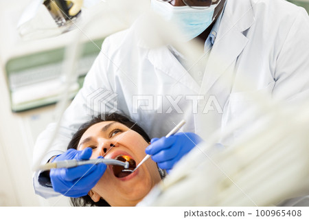 Female patient during dental treatment in dentist office 100965408