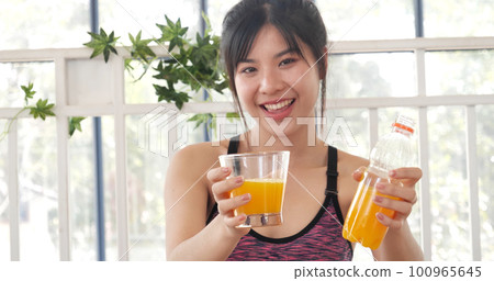 Women hands holding cold orange juice fresh fruit cool drinking. Asian women smile laugh look at camera health care home fitness lifestyle. Beautiful female pouring orange juice from cocktail bottle 100965645