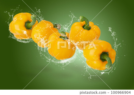 Creative layout made from yellow Bell Pepper and water splashing on a Green background 100966904