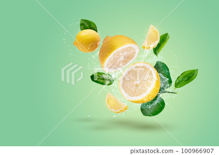 Creative layout made form Lemon fruit and lemon slices and water splashing on a green background. 100966907