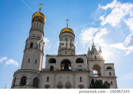 Ivan the Great Bell Tower, with Assumption Belfry on the right in Moscow Kremlin. Blue sky background with sunbeams 100967245