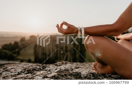 Well looking middle aged woman with long hair, fitness instructor in leggings and tops doing stretching and pilates on the rock near forest. Female fitness yoga routine concept. Healthy lifestyle 100967799