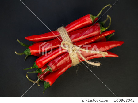 Chili pepper isolated on a black background. Knitted hot chili pepper tied with a rope. Chili hot pepper clipping path. Chili pepper isolated on a black background. Knitted hot chili pepper tied with a rope. Chili hot pepper clipping path. 100968042