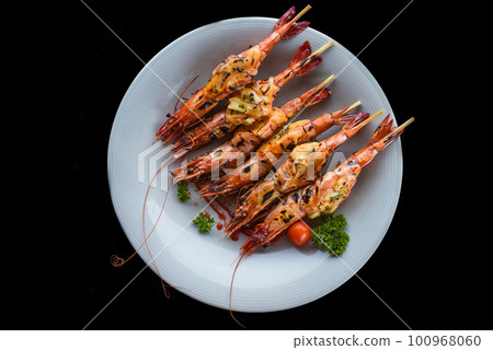 Six grilled shrimps with cheese on blue plate isolated on black background top view 100968060