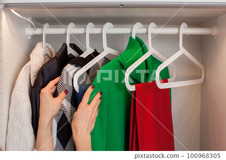 Caucasian young woman puts clothes in the closet. Magic of Tidying Up. Caucasian young woman puts clothes in the closet. Magic of Tidying Up. 100968305