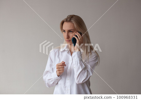 A young woman in a white shirt talking on the phone. 100968331