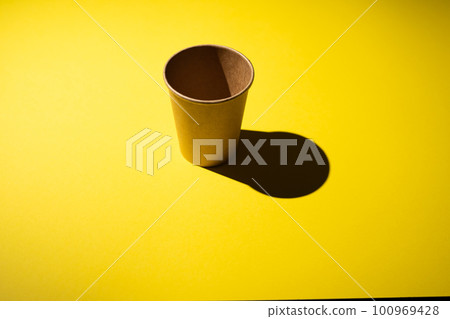 Cardboard coffee cup on yellow background with shadow. 100969428