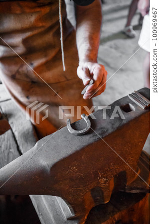 The blacksmith forging glowing horseshoe 100969467