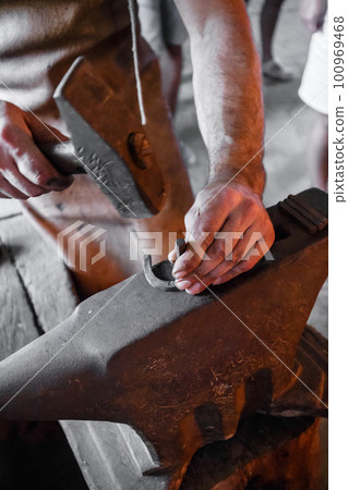 The blacksmith forging glowing horseshoe The blacksmith forging glowing horseshoe 100969468