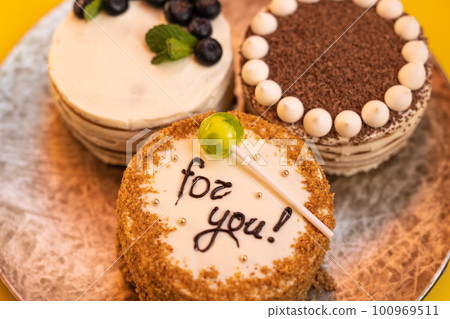 Three bento cakes with different designs on a yellow background. 100969511