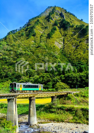 Tadami Line Kiha E120 train crossing the Managawa Bridge in autumn and Mt. Gamo (Tadami Town, Fukushima Prefecture, October) Tadami Line Kiha E120 train crossing the Managawa Bridge in autumn and Mt. Gamo (Tadami Town, Fukushima Prefecture, October) 100970587
