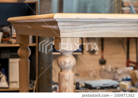Wooden dining table with carved leg of solid oak and metal frame build process in workshop close up view Wooden dining table with carved leg of solid oak and metal frame build process in workshop close up view 100971382