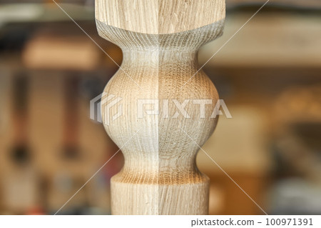 Wooden carved leg of solid oak of dining table in workshop extreme close up view 100971391