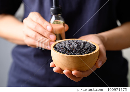 Black sesame seed and oil holding by hand, Food ingredients in Asian cuisine 100971575