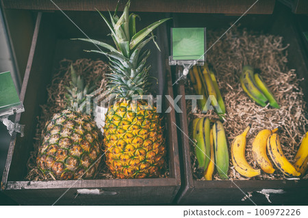 Pineapples and banana fruits for sale at farmer's market natural organic food. Fruit in wooden basket. 100972226