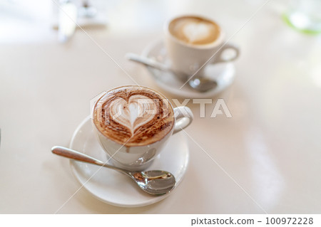 Latte coffee cups and cappuccino milk mug at restaurant table. 100972228