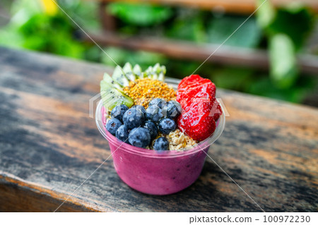 Acai bowl healthy breakfast in to go plastic takeout bowl frozen yogurt smoothie with fresh fruits, berries, blueberries at Hawaii cafe. Foodie food snack. 100972230