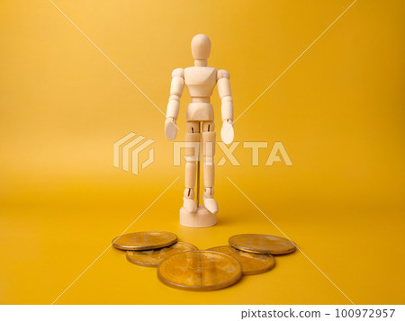 Wooden mannequin stand infront bitcoins on a yellow background. 100972957