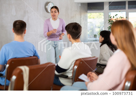 Young female professor explaining subject to group of students 100973731