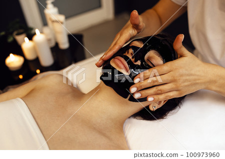 Pretty brunette female with cosmetic mask on her face. Skin care c Pretty brunette female with cosmetic mask on her face. Skin care c 100973960