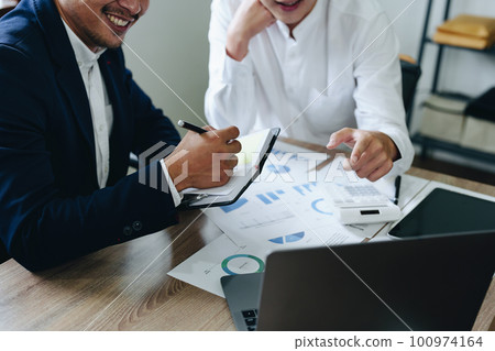 Young economists or accountants or financiers and investors are reviewing budget documents and using computers to study impact and risk assessments on corporate investment management 100974164