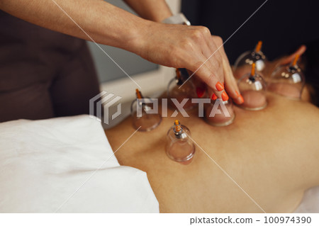 Faceless masseur rubbing back of customer 100974390