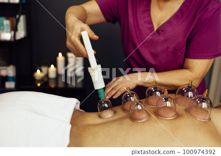 Faceless masseur rubbing back of customer Faceless masseur rubbing back of customer 100974392