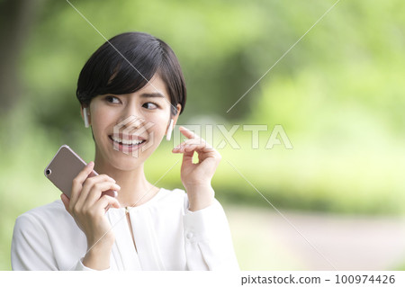 年輕女子在戶外用智能手機聽音樂 100974426