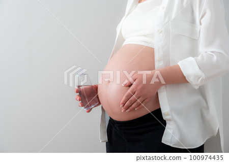 Pregnant woman applying cosmetic oil on her belly for healing stretch marks and skin elasticity 100974435