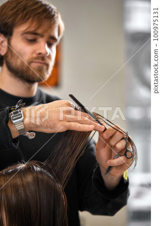 Professional male hairdresser cutting female hair in salon Professional male hairdresser cutting female hair in salon 100975131