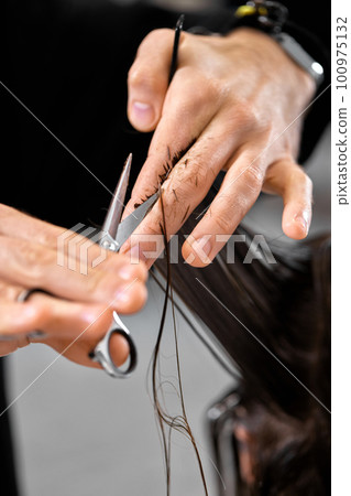 Professional male hairdresser cutting female hair in salon 100975132