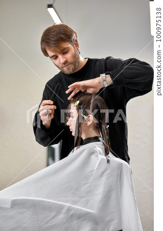 Professional male hairdresser cutting female hair in salon Professional male hairdresser cutting female hair in salon 100975138